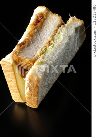 Thick-cut pork cutlet sandwich photographed alone against a black background 133215496