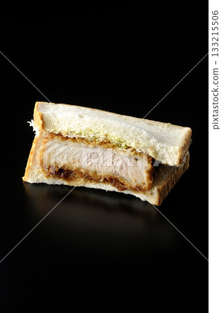 Thick-cut pork cutlet sandwich photographed alone against a black background Thick-cut pork cutlet sandwich photographed alone against a black background 133215506