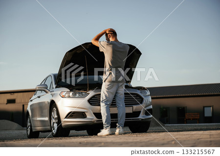 Trying to repair the broken automobile. Man is with his car outdoors 133215567