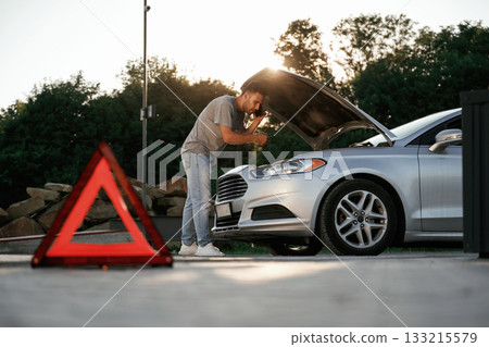 Under the sunlight, red sign, accident, broken automobile, repair. Man is with his car outdoors 133215579