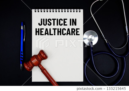 Notepad with "Justice In Healthcare" a pen, gavel, and stethoscope on a black background 133215645