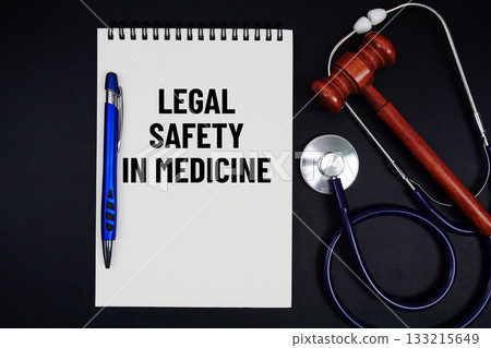 Notepad with "Legal Safety In Medicine" a pen, gavel, and stethoscope on a black background 133215649