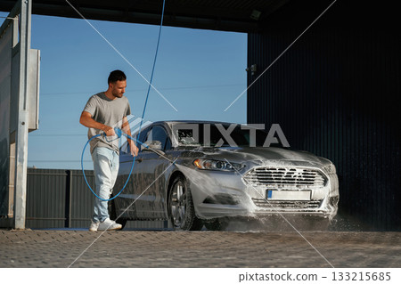 Water high pressure stream, car wash. Man is with his automobile outdoors 133215685