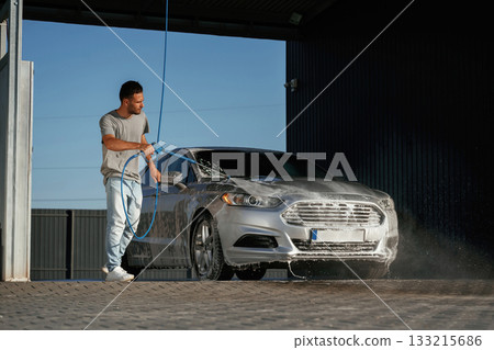 Water high pressure stream, car wash. Man is with his automobile outdoors Water high pressure stream, car wash. Man is with his automobile outdoors 133215686