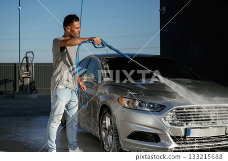 Water high pressure stream, car wash. Man is with his automobile outdoors Water high pressure stream, car wash. Man is with his automobile outdoors 133215688