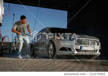 Walking around and washing the automobile. Man is with his car outdoors 133215691