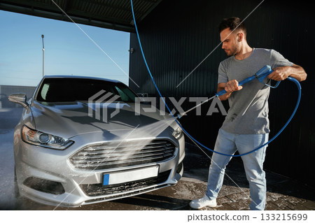 Standing and washing the automobile. Man is with his car outdoors 133215699