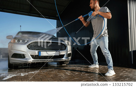 Standing and washing the automobile. Man is with his car outdoors 133215702