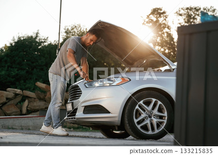 Hood is opened, repairing. Man is with his car outdoors Hood is opened, repairing. Man is with his car outdoors 133215835