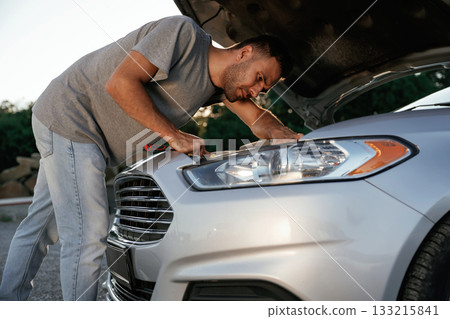 Breakdown, hood is opened, repairing. Man is with his car outdoors 133215841