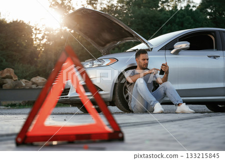 Broken car, red sign. Man is with his automobile outdoors 133215845