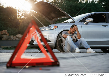 Broken car, red sign. Man is with his automobile outdoors 133215846