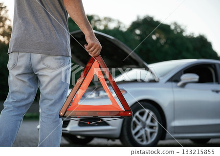 Holding red sign, broken automobile. Man is with his car outdoors Holding red sign, broken automobile. Man is with his car outdoors 133215855