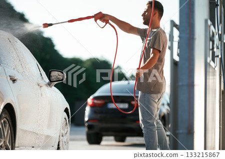 Washing the automobile. Man is with his car outdoors 133215867