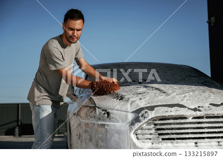 Cleaning the surface, car wash. Man is with his automobile outdoors 133215897