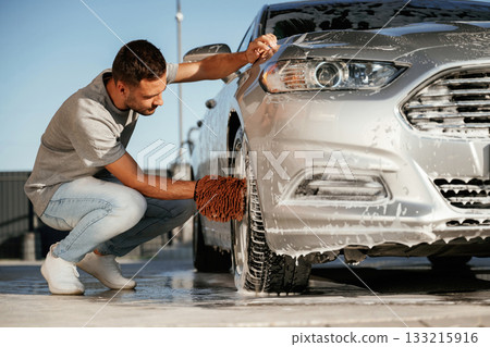Sitting and washing the automobile. Man is with his car outdoors 133215916