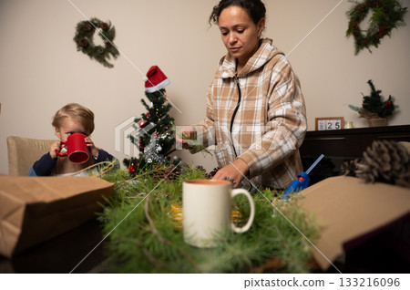 Family Christmas Craft At Home: Woman And Child Decorating Wreaths With Greens 133216096