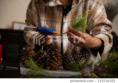 Person Crafting Pine Cone Christmas Decorations With Glue Gun At Home 133216102