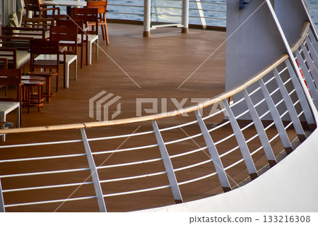 Outdoor seats on passenger ship deck with the calm seascape. Cruise ship deck. Wooden promenade deck on a luxury cruise liner. Ocean in background. 133216308