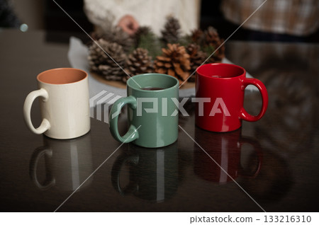 Cozy Home Scene With Colorful Mugs And Pinecone Christmas Decor On Table 133216310