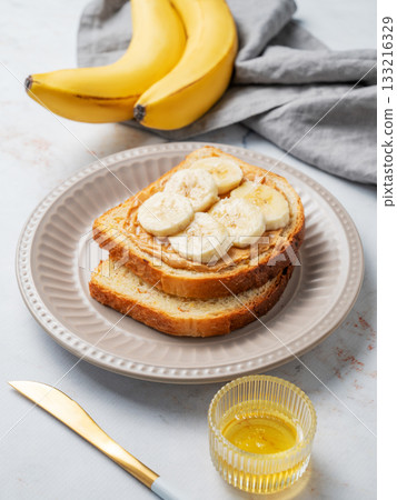 Peanut butter sandwich and banana on a plate on a marble background with honey, Peanut butter sandwich and banana on a plate on a marble background with honey, 133216329