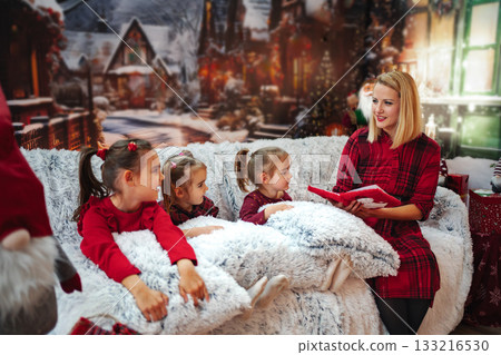 Mother reading Christmas storybook to her children Mother reading Christmas storybook to her children 133216530