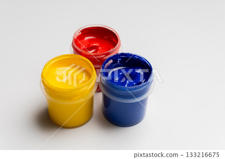 Jars of multi-colored gouache on a white background. Blue, red, and yellow traffic light colors. 133216675
