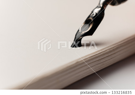 A close-up macro shot of a drop of ink on a notepad. A fountain pen is nearby. Retro office concept. 133216835