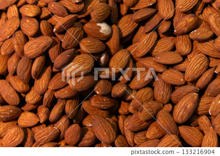 Delicious roasted almonds with spices are sold in large quantities at a vegetable market. Close-up. Almond background. 133216904