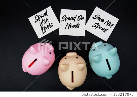 Three piggy banks with sticky note written "Spend with Limits," "Spend On Needs," and "Save Not Spend," financial planning goals on a black background Three piggy banks with sticky note written "Spend with Limits," "Spend On Needs," and "Save Not Spend," financial planning goals on a black background 133217073