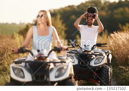 Enjoying the ride, on the field. Man and woman are on ATV outdoors 133217102