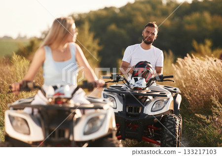Enjoying the ride, on the field. Man and woman are on ATV outdoors 133217103