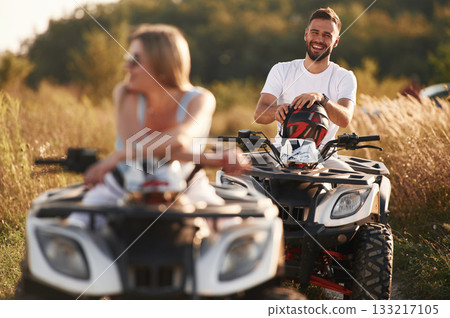 Enjoying the ride, on the field. Man and woman are on ATV outdoors 133217105