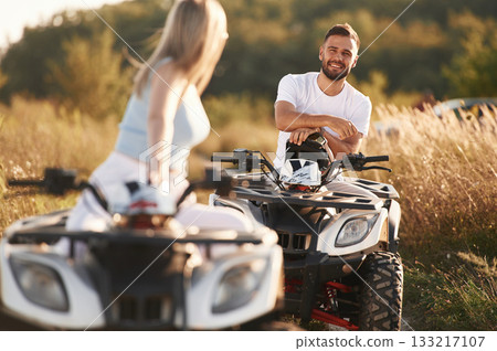 Standing, taking a break. Man and woman are on ATV outdoors Standing, taking a break. Man and woman are on ATV outdoors 133217107