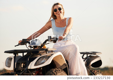 Happy beautiful woman in sunglasses is on the ATV, outdoors 133217130