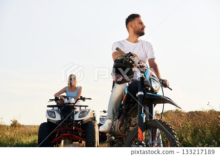 Get ready for the ride. Man on motorcycle and woman is on the ATV, outdoors together Get ready for the ride. Man on motorcycle and woman is on the ATV, outdoors together 133217189