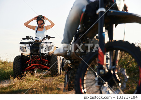 Man on motorcycle and woman is on the ATV, outdoors together Man on motorcycle and woman is on the ATV, outdoors together 133217194