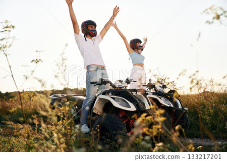 Hands raised up. Man and woman are on ATV outdoors Hands raised up. Man and woman are on ATV outdoors 133217201