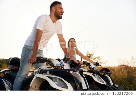 Under sunlight. Man and woman are on ATV outdoors Under sunlight. Man and woman are on ATV outdoors 133217206