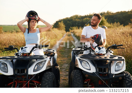 Front view. Man and woman are on ATV outdoors Front view. Man and woman are on ATV outdoors 133217215