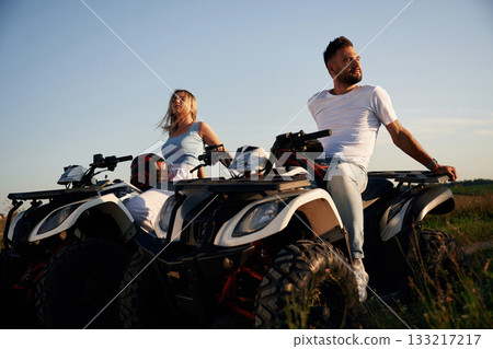 Sitting, taking a break. Man and woman are on ATV outdoors 133217217
