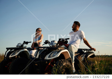 Sitting, taking a break. Man and woman are on ATV outdoors 133217220