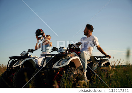 Sitting, taking a break. Man and woman are on ATV outdoors Sitting, taking a break. Man and woman are on ATV outdoors 133217221