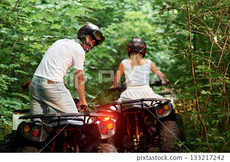 Green forest, adventure. Man and woman are on ATV outdoors 133217242