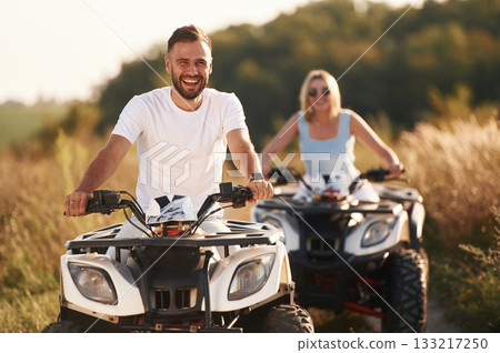 Cheerful facial expression. Man and woman are on ATV outdoors 133217250