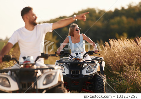 Countryside road, front view. Man and woman are on ATV outdoors 133217255