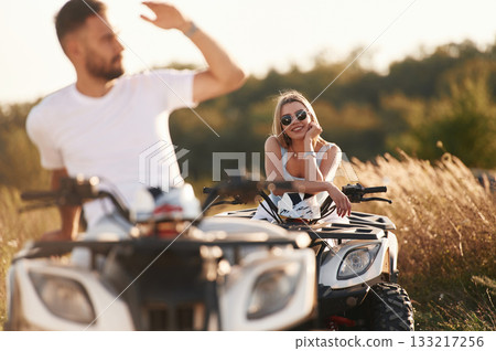 Countryside road, front view. Man and woman are on ATV outdoors Countryside road, front view. Man and woman are on ATV outdoors 133217256