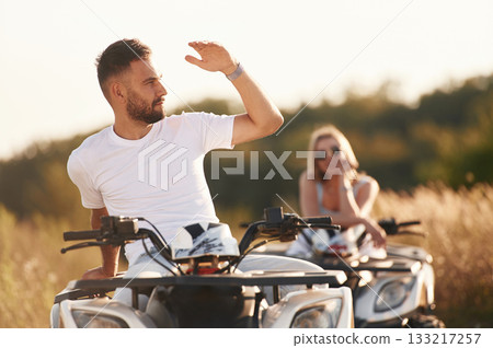 Countryside road, front view. Man and woman are on ATV outdoors Countryside road, front view. Man and woman are on ATV outdoors 133217257