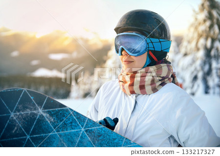 Close up of the ski goggles of a woman with the reflection of snowed mountains. Ski Woman on the sunset background 133217327