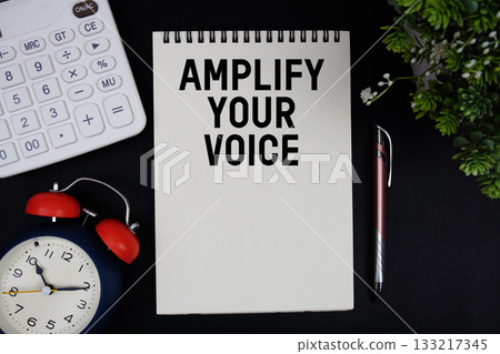 Amplify Your Voice text with calculator with alarm clock on black background 133217345